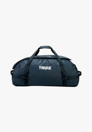 Grand sac polochon Thule bleu foncé avec double sangle de transport et compartiment principal zippé sur fond blanc.