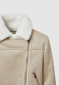 Giubbotto in suede sintetico beige con colletto in pelo bianco, dotato di chiusura con zip e tasche con zip, dalla texture morbida e dai lineamenti puliti.