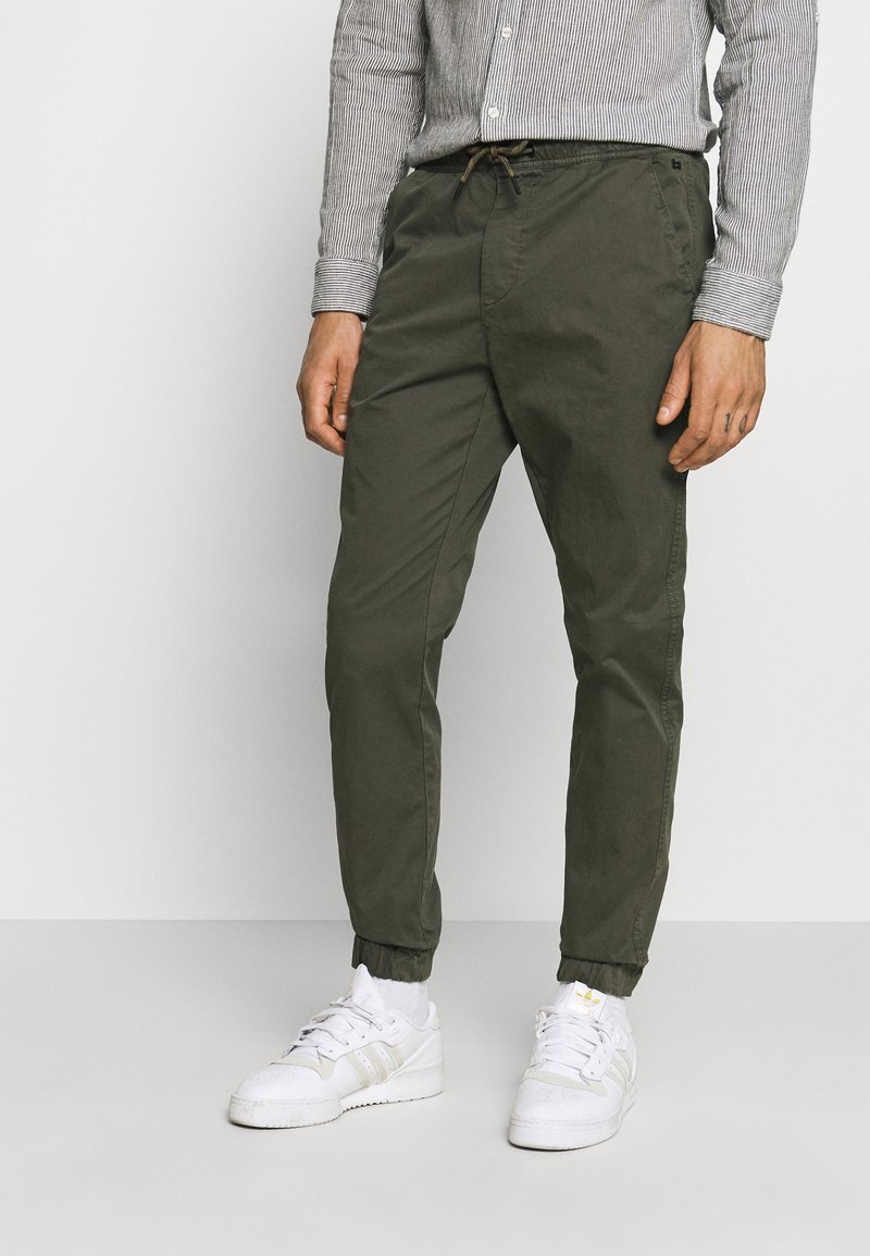 Olive green tapered pants with an elastic waistband and drawstring. Features cuffed ankles and a smooth cotton blend material.