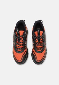 Chaussures de sport noires et orange en matériau mesh, avec un bout arrondi, des accents texturés et des lacets contrastés, ainsi qu'une semelle rembourrée.