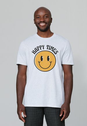 T-shirt en coton gris avec un grand graphique d'un visage souriant jaune et le texte "HEURES HEUREUSES" au-dessus. Manches courtes et design col rond.