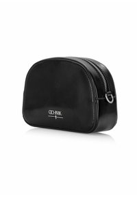 Czarna skórzana kosmetyczka o gładkiej fakturze, zaokrąglonym kształcie, srebrnym suwak i wytłoczonym logo z przodu. Kompaktowa i funkcjonalna.