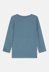 Langermet, ribbet topp i dempet blå. Myk stoff, rund hals og rett kant. Ingen synlige mønstre eller tilleggsdetaljer.