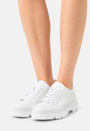 Zapatillas blancas con cordones, con una parte superior de cuero texturizado y suelas de goma gruesas, que cuentan con refuerzos en la puntera y el talón para mayor durabilidad.