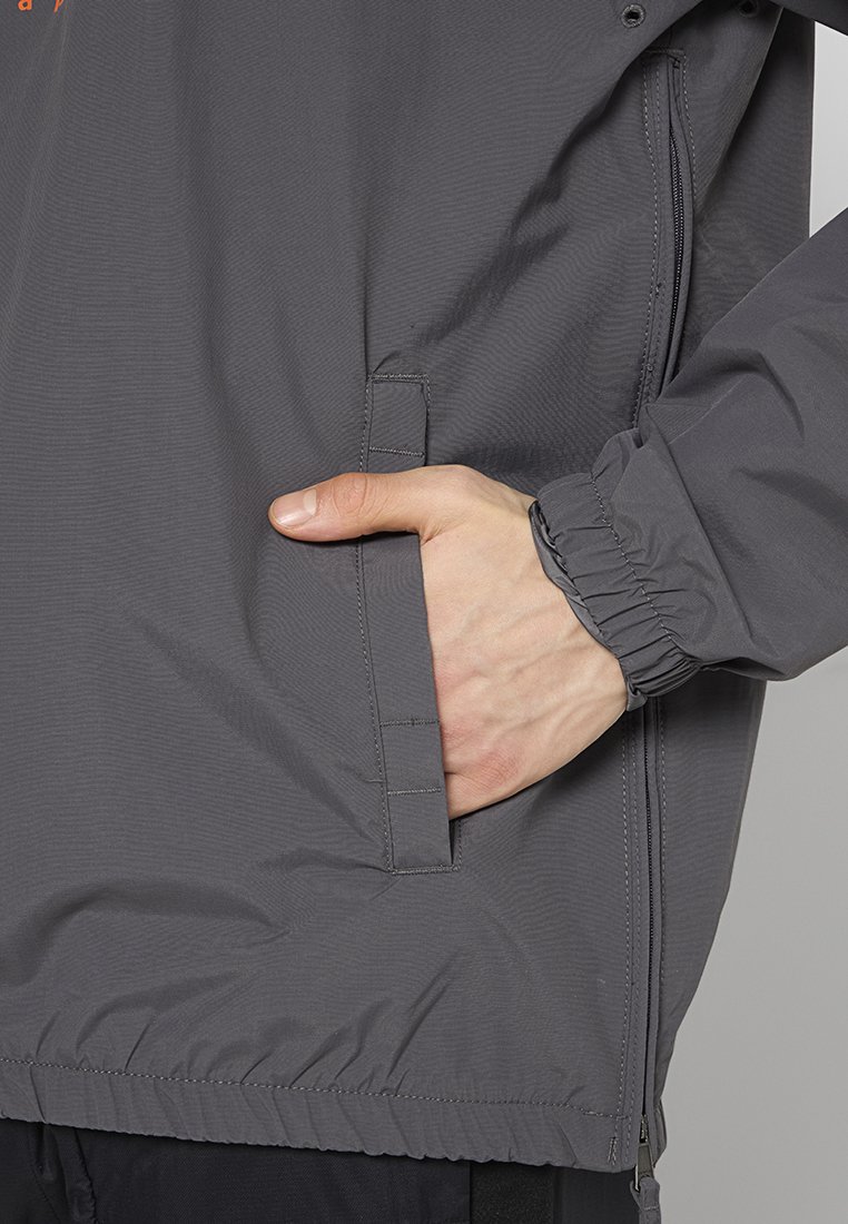 Szara kurtka wiatrówka z elastycznym mankietem, boczną kieszenią oraz marszczonym dołem, charakteryzująca się gładką teksturą i subtelnym połyskiem.