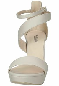 Sandal con tacco alto beige, con cinturini incrociati, suola platform e una delicata cinghia alla caviglia. Realizzata in pelle liscia con finitura lucida.