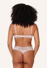 Set di completino con slip e reggiseno in beige chiaro, decorato con pizzo. Il reggiseno presenta spalline regolabili e chiusura a gancio sul retro, con dettagli in pizzo floreale.