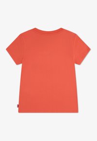 Μονόχρωμο κοντομάνικο t-shirt κοραλλί με στρογγυλή λαιμόκοψη, ορατή ραφή και μια μικρή ετικέτα στη ραφή αριστερά στο τελείωμα.