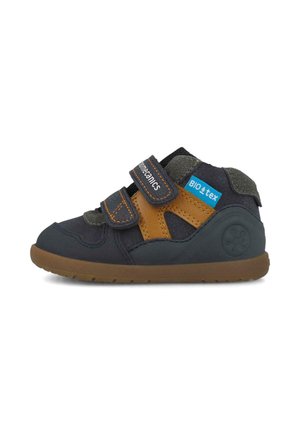 Zapato para niño pequeño azul marino y marrón con dos tiras de velcro ajustables y una suela de goma texturizada.
