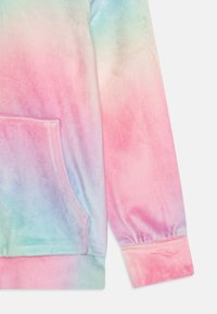 Miękki rękaw bluzy z kapturem i kieszeń w pastelowych gradientowych kolorach różu, niebieskiego i zieleni, z elastycznym mankietem i widocznymi detalami szwów.