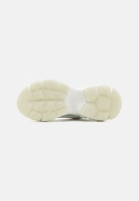 Suela de zapato con una superficie de goma texturizada en color crema, que presenta un diseño segmentado con patrones hexagonales y áreas reforzadas para mayor soporte.