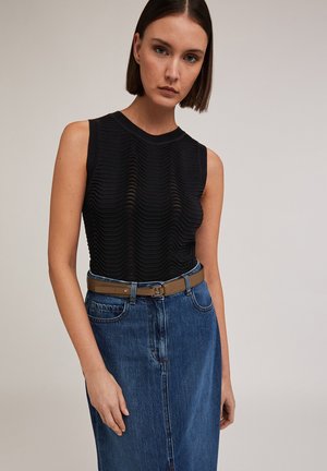 Top senza maniche nero con texture ondulata, abbinato a una gonna di jeans a vita alta. Una cintura marrone mette in risalto la vita con un semplice dettaglio della fibbia.