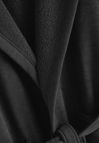 Rochie neagră cu căptușeală din fleece texturat și exterior neted. Are guler tip șal, curea de legat și buzunare laterale.