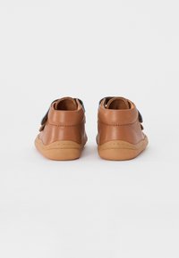 Braune Lederschuhe mit niedrigem Schnitt und abgerundeter Ferse. Sie verfügen über eine flexible Sohle und blaue Textilakzente oben. Gestickte Details sind vorhanden.