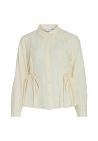 Chemise à boutons d'un créme léger avec col, manches longues et détails à cordon sur les côtés. Fabriquée en tissu texturé.