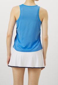 Débardeur de sport bleu avec un col rond et un dos nageur, associé à une jupe évasée blanche bordée d'un liseré bleu marine à l'ourlet.