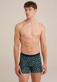 Sötétzöld anyagú boxer nadrág, világoskék virágmintával. Tengerészkék elasztikus derékpánttal és testhezálló fazonnal rendelkezik.