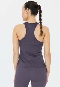 Lila Sporttanktop mit Racerback-Design, aus glattem, elastischem Material. Verfügt über eine taillierte Passform und minimalistischen Nähdetails.