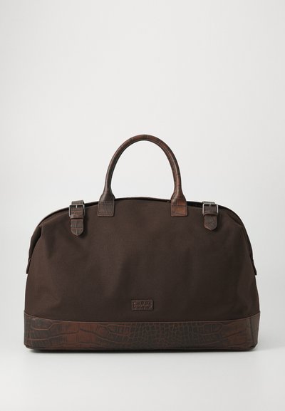 Sac de sport en toile brune avec un fond en cuir gaufré crocodile, deux poignées en cuir et des accents de boucle en métal argenté. Texture lisse sur l'ensemble.