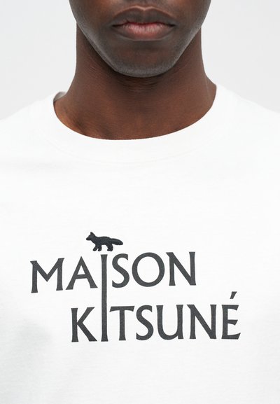 Biela bavlnená tričko s čiernym potlačeným textom "MAISON KITSUNÉ" a čiernou grafikou líšky nad textom, s kruhovým výstrihom.
