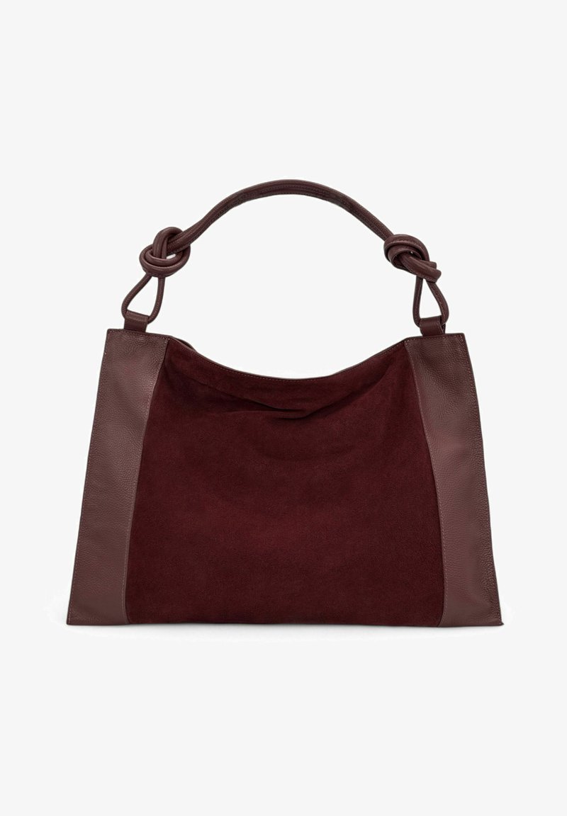 Sac fourre-tout en velours bordeaux avec des accents en cuir marron, doté d'une anse nouée. Texture lisse sur le cuir, texture douce sur le velours.