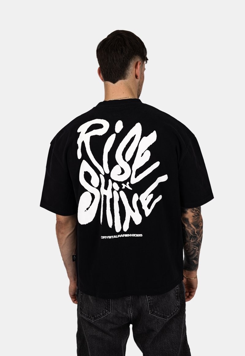 Czarny bawełniany t-shirt z wyrazistym białym napisem "RISE x SHINE" na plecach. Krótkie rękawy i luźny krój.