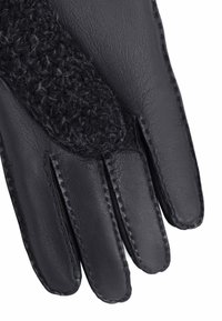 Gant en cuir noir avec un panneau tricoté texturé sur le dessus. Le gant a une forme ajustée et une couture contrastante le long des coutures.