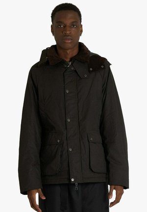 Giacca nera con colletto in velluto a coste marrone, bottoni a pressione, due tasche frontali e vestibilità comoda. Il materiale sembra resistente e testurizzato.