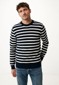Sweter w niebiesko-kremowe paski, z długimi rękawami, okrągłym dekoltem oraz ściągaczami przy rękawach i u dołu, wykonany z teksturowanej dzianiny. Noszony z niebieskimi dżinsami.