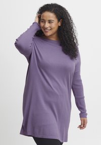 Tunic viola a maniche lunghe realizzata in tessuto morbido, con una vestibilità ampia, scollatura rotonda e spacco laterale per facilitare i movimenti.
