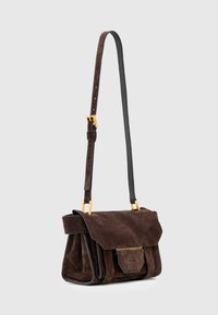 Brązowa skórzana torebka z klapą, regulowanym czarnym paskiem, złotymi akcentami oraz małą przednią kieszonką.