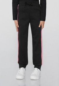 Schwarze Jogginghose mit einem Kordelzugbund, die pinke und silberne seitliche Streifen aufweist. Gerippte Bündchen und eine weiche Textur vervollständigen das Design.