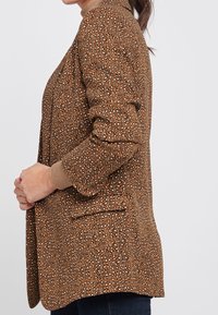 Bruine blazer met een iets losse pasvorm, gestructureerde stof, luipaardprint, geribbelde manchetten en zijzakken.
