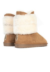 Tanmocka ank stövlar med en mjuk, krämfärgad syntetpälsmanschett. Har en platt, texturerad gummisula och en logotyp-patch på hälen.