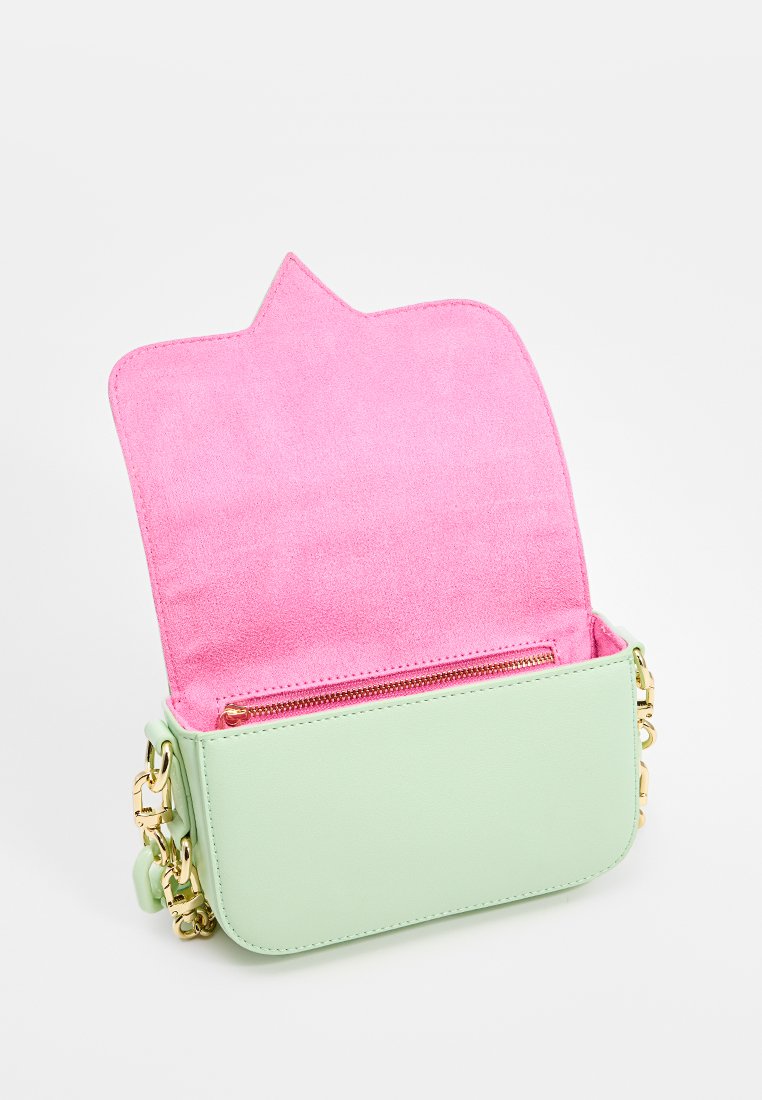 Bolso de cuero verde con un interior de ante rosa. Cuenta con un bolsillo con cremallera y herrajes en dorado. La solapa tiene un diseño puntiagudo.