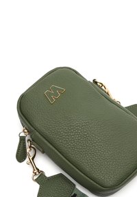 Sac à main en cuir vert avec une surface texturée, de forme rectangulaire, matériel doré et un logo en relief "M" proéminent à l'avant.