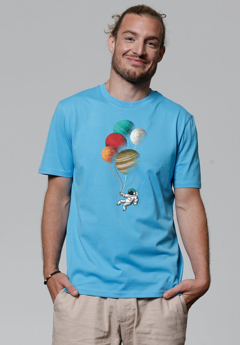 Lichtblauwe katoenen t-shirt met een astronaut graphic die kleurrijke planetvormige ballonnen vasthoudt in diverse tinten en texturen.