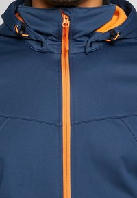 Veste bleu marine avec une fermeture éclair orange et des accents assortis, dotée d'un col montant et d'une capuche ajustable, fabriquée en matière synthétique lisse.