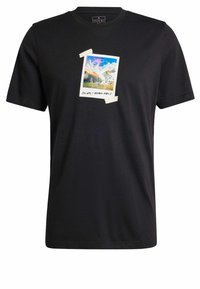T-shirt en coton noir présentant un graphique à l'avant d'un polaroïd d'un paysage coloré, avec des accents de ruban aux coins. Manches courtes, col rond.