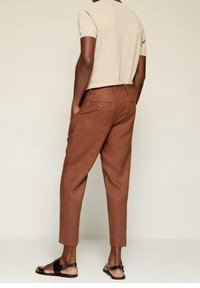 Pantalon en lin marron à coupe décontractée, avec des poches latérales et des poches passepoilées à l'arrière, associé à une chemise à manches courtes beige clair.