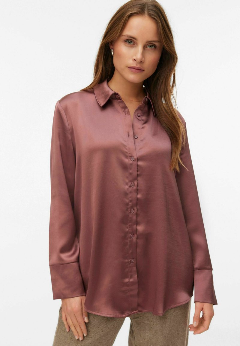 Langærmet, knaplukket skjorte i mauve satin. Har en klassisk krave og subtil glans, med en afslappet pasform og manchetterede ærmer.