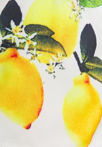 Citrons jaunes avec des feuilles vertes et de petites fleurs blanches sur un fond clair. Un tissu texturé capture des couleurs vives et des motifs détaillés.