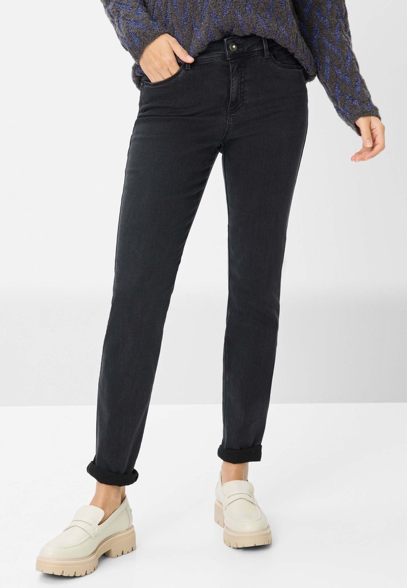 Zwarte denim jeans met een slim fit, voorzien van een knoopsluiting, voorkruiden en omgeslagen broekspijpen, gecombineerd met witte chunky loafers.