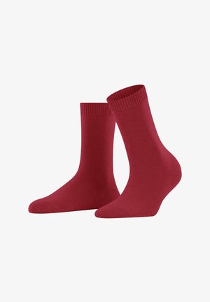 Une paire de chaussettes classiques rouges foncées exposées sur un fond blanc, l'une debout et l'autre inclinée diagonalement.