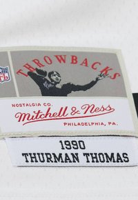 Etikett mit "Throwbacks" in rotem Text, einem schwarz-weißen Grafik eines Spielers und den Markendetails "Mitchell & Ness" sowie "1990 THURMAN THOMAS."