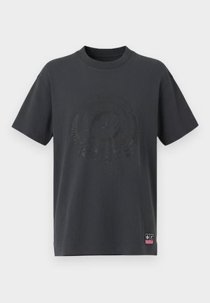 T-shirt de algodão cinza escuro com gola redonda, mangas curtas e um logotipo relevo tonal e elementos decorativos na frente. Pequeno rótulo rosa na bainha.