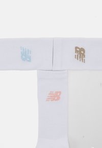 Calcetines blancos con logos de colores: azul claro, rosa y marrón. Diseño acanalado en la parte superior y textura suave en todo el calcetín. Sencillos y funcionales.