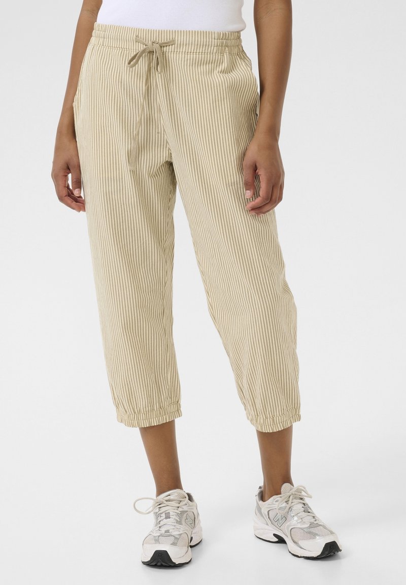 Pantalon court beige clair à fines rayures verticales, taille élastique avec cordon de serrage, poches latérales et poignets froncés.
