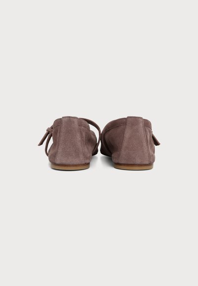 Paire de chaussures plates en suède marron avec petit talon et détail nœud, vues de dos sur fond blanc.