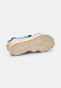Sandal blu in suede con una suola in gomma beige testurizzata, dotata di una fascia fissata da una fibbia metallica. Logo del brand visibile sulla suola.
